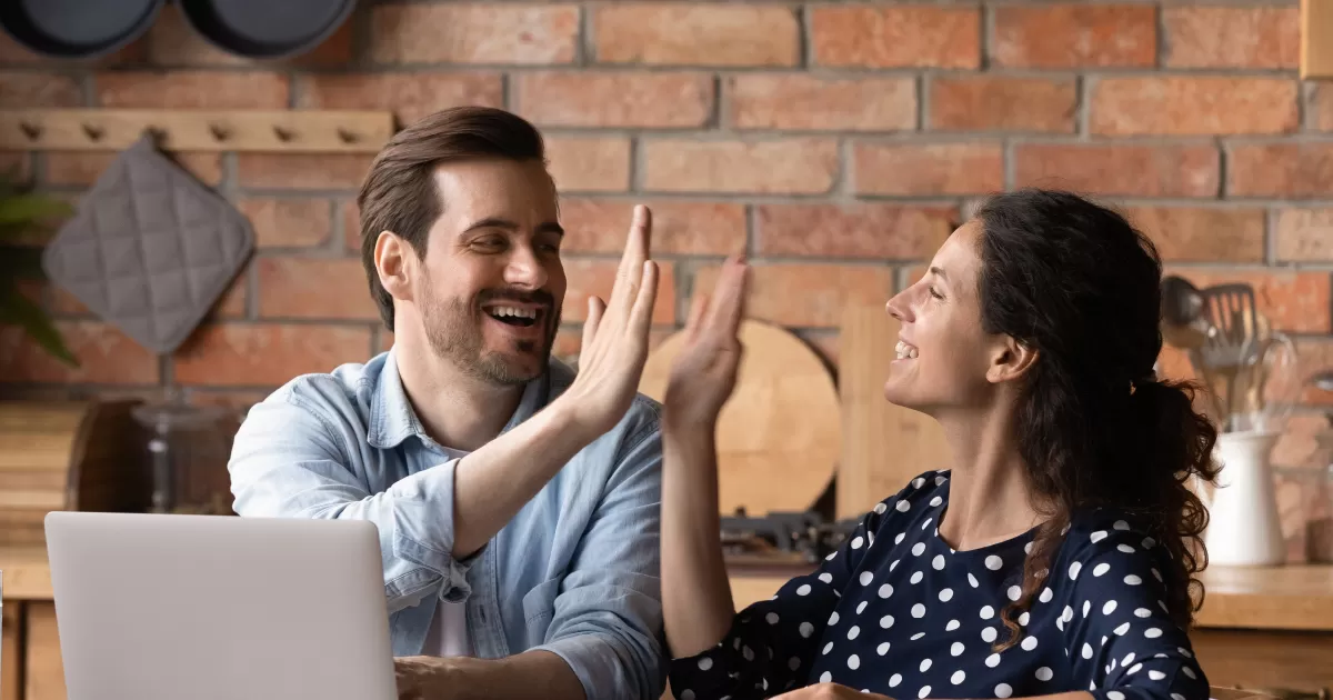 Couple high-fiving in their kitchen.