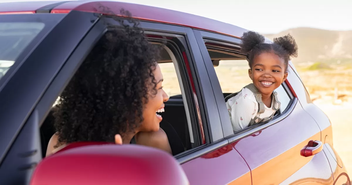 Mom and daughter smiling at each other in their car